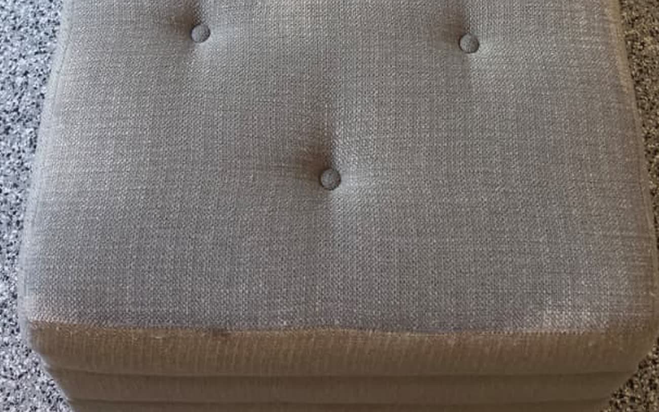 Tufted upholstered bench with grey, soiled-looking fabric before cleaning
